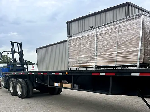 Crated fence panels on a flatbed trailer with a forklift ready to unload at a partner warehouse