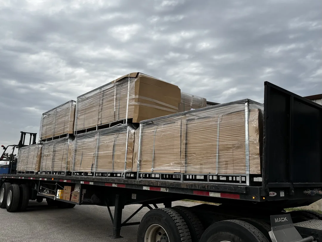 Crated, shrink-wrapped steel fence panels loaded on a flatbed for the jobsite