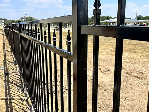 Close-up of a steel fence post cap, bracket and gloss black powder-coat finish