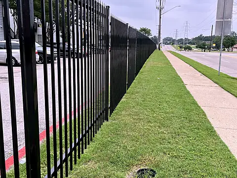 Three-rail pointed-picket security fence along a street frontage and sidewalk