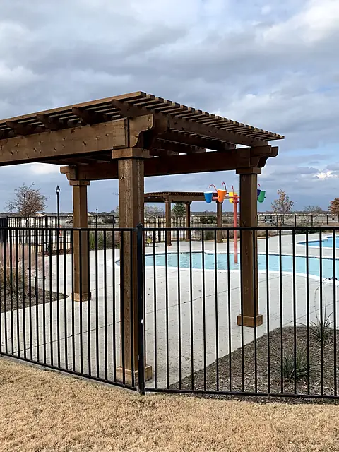 Flat-top fence around a community pool with a wood pergola