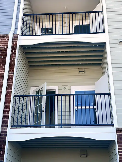Balcony railing with top rail and brackets on a two-story apartment walkway